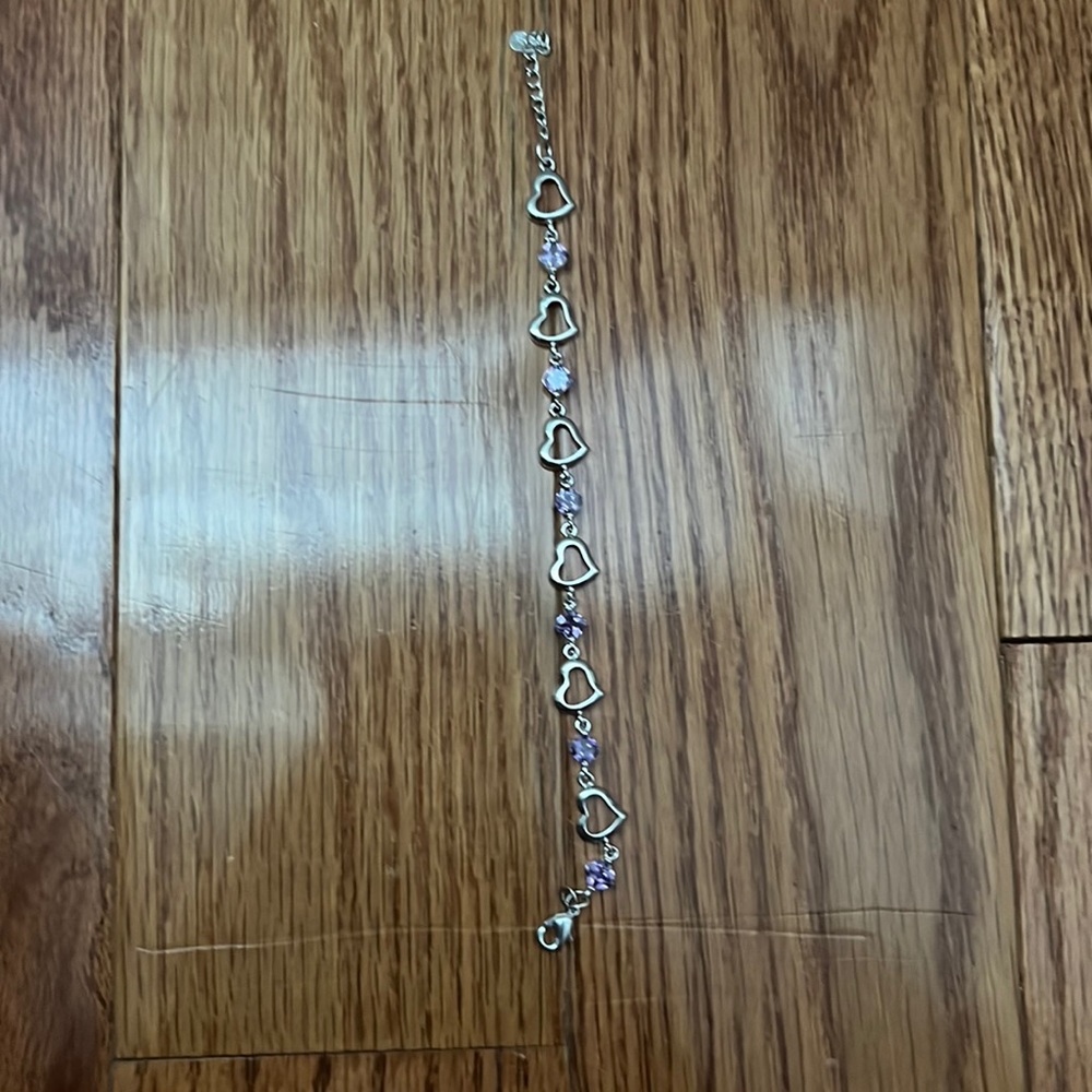 Silver heart bracelet with purple gems. One size and is cleaned